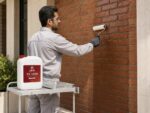بانوی مهندس با شال زرشکی در حال بررسی نمای آجری پوشش‌داده‌شده با محلول JAM SH-1000